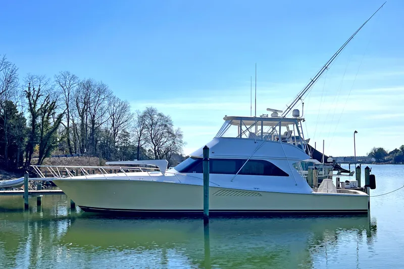 Slide: The Image of 1999 Viking 55 yacht docked on a serene lake with clear blue skies. - 1