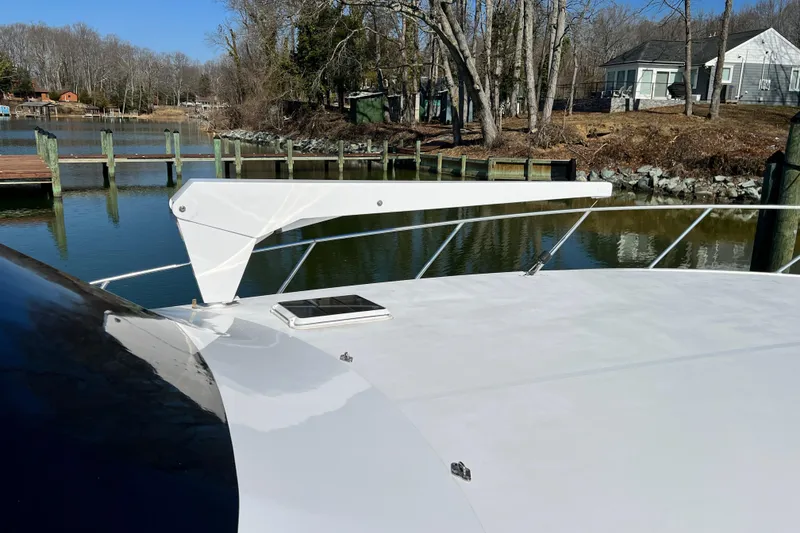 Slide: The Image of 1999 Viking 55 yacht docked by a serene waterfront with trees and houses. - 13