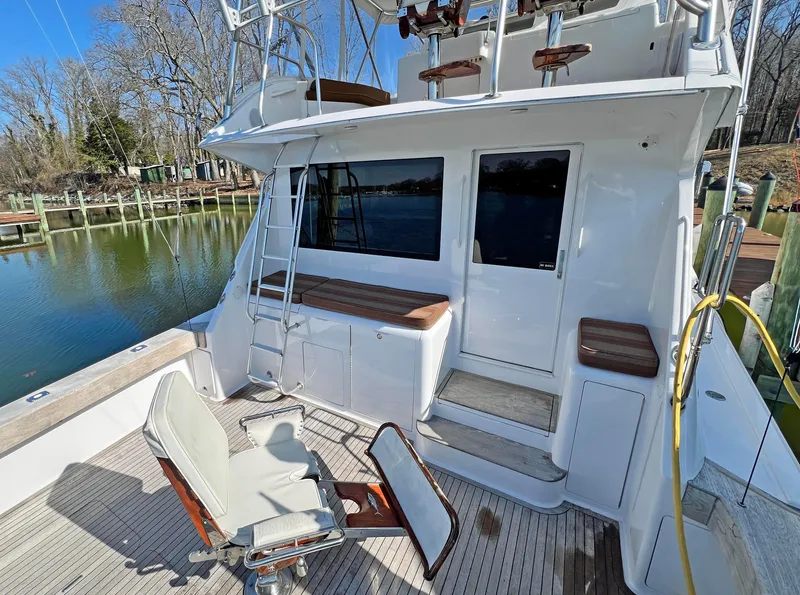 Slide: The Image of 1999 Viking 55 yacht deck with seating, ladder, and scenic waterfront view. - 15