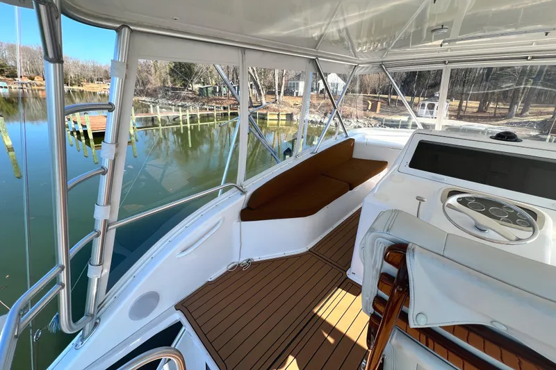 Slide: The Image of 1999 Viking 55 yacht cockpit with seating, wooden deck, and steering console by a serene waterfront. - 19