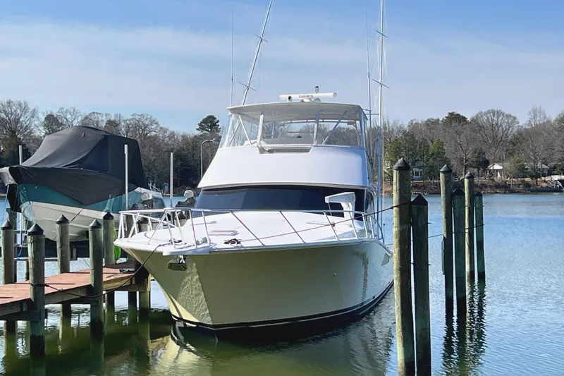 Slide: The Image of 1999 Viking 55 yacht docked on a calm lake with clear skies. - 2