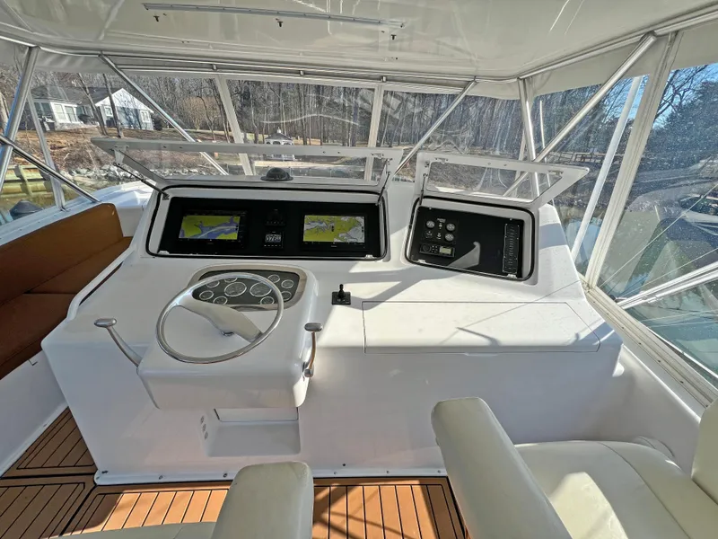 Slide: The Image of 1999 Viking 55 yacht helm with navigation screens and steering wheel, featuring wood flooring. - 21