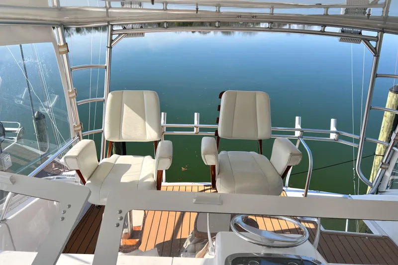 Slide: The Image of 1999 Viking 55 yacht helm with two white captain chairs overlooking calm water. - 25