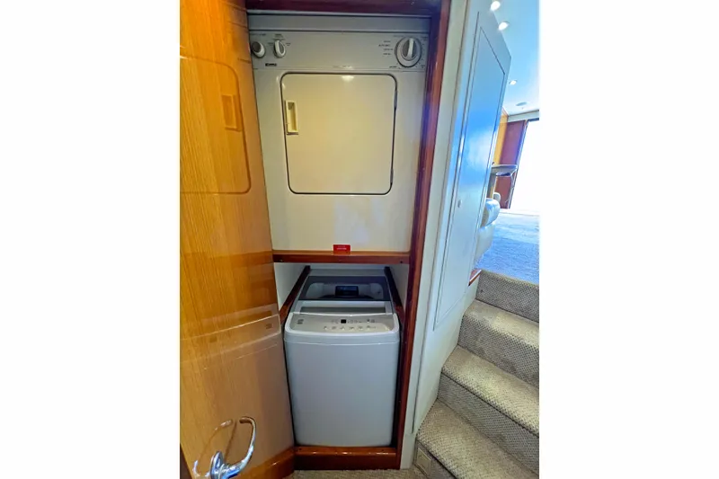 Slide: The Image of Laundry area inside a 1999 Viking 55 yacht, featuring a compact washer and dryer. - 35