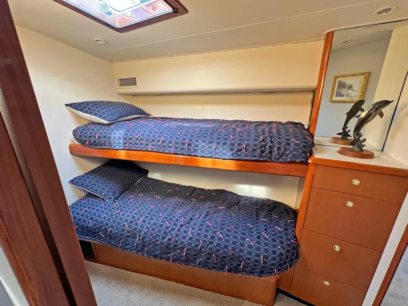 Slide: The Image of Bunk beds in a 1999 Viking 55 yacht cabin with blue bedding and wooden cabinetry. - 36
