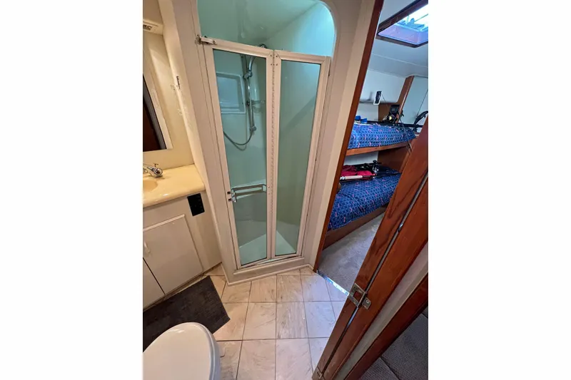 Slide: The Image of Bathroom and bunk area in 1999 Viking 55 yacht, featuring shower and skylight. - 38