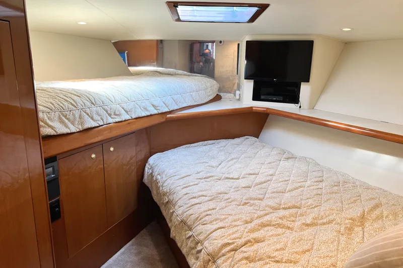 Slide: The Image of 1999 Viking 55 yacht interior with twin beds, wooden cabinetry, and a mounted TV. - 44
