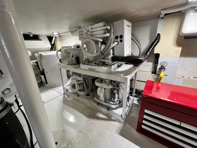 Slide: The Image of Engine room of a 1999 Viking 55 yacht, featuring mechanical equipment and storage. - 53