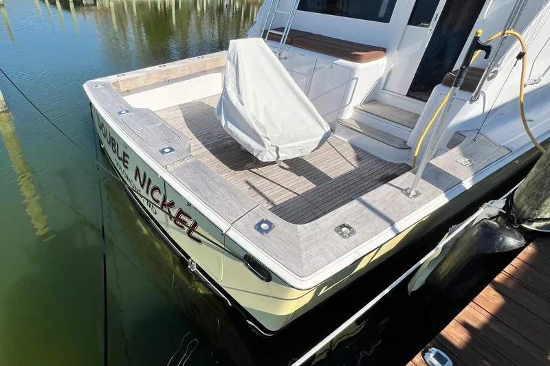 Slide: The Image of 1999 Viking 55 yacht docked, featuring spacious deck and covered seating area. - 8