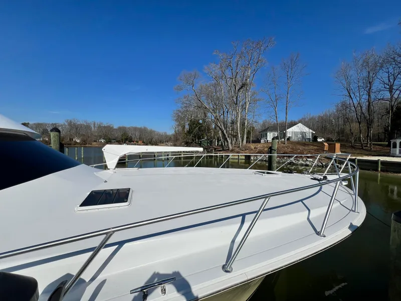Slide: The Image of 1999 Viking 55 yacht docked by a serene riverside with trees and houses. - 9