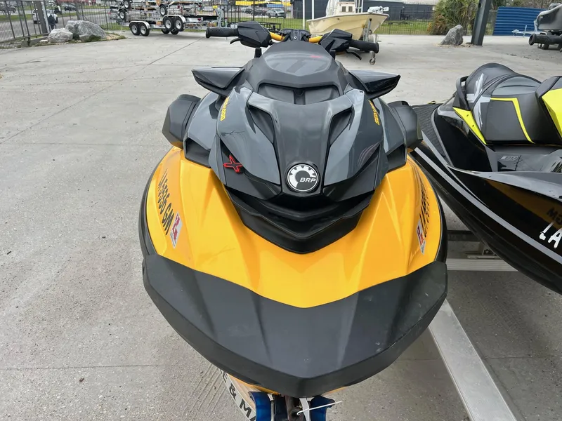Slide: The Image of 2021 Sea-Doo RXP-X 300 jet ski in yellow and black, parked outdoors. - 2