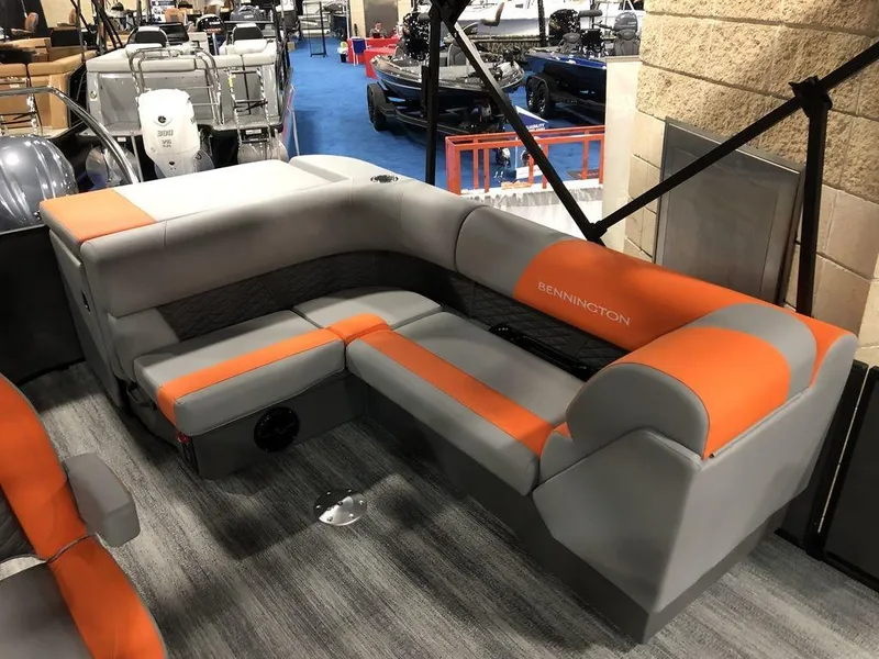 Slide: The Image of 2025 Bennington S L-Bench 23 SL boat seating, gray and orange upholstery, indoor display. - 4