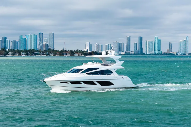Slide: The Image of 2016 Sunseeker Manhattan 65 yacht cruising near a city skyline. - 13
