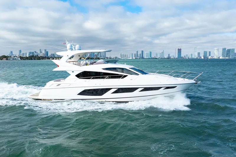 Slide: The Image of 2016 Sunseeker Manhattan 65 yacht cruising on open water with city skyline backdrop. - 17