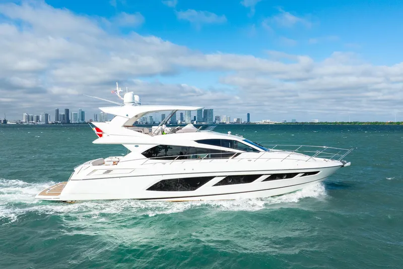 Slide: The Image of 2016 Sunseeker Manhattan 65 yacht cruising on open water with city skyline backdrop. - 22