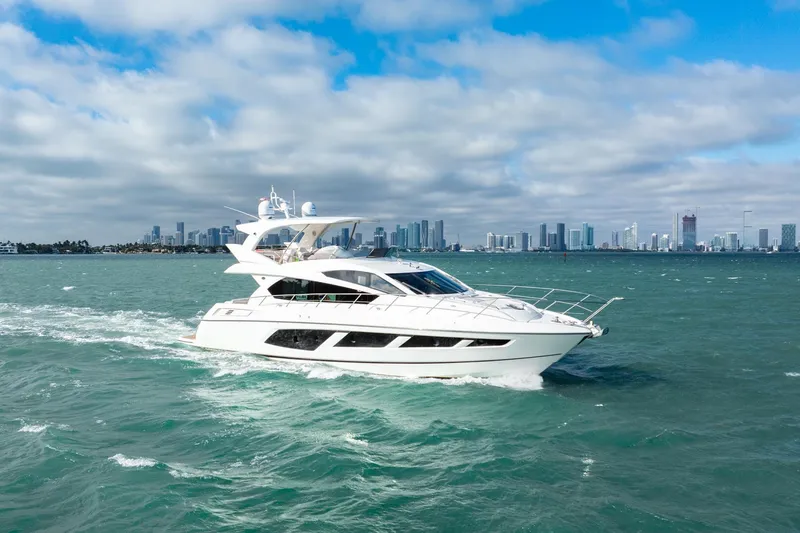 Slide: The Image of 2016 Sunseeker Manhattan 65 yacht cruising on open water with city skyline backdrop. - 23