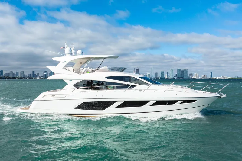 Slide: The Image of 2016 Sunseeker Manhattan 65 yacht cruising on open water with city skyline backdrop. - 25
