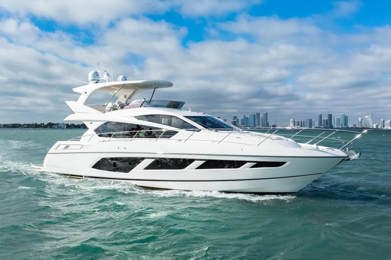 Slide: The Image of 2016 Sunseeker Manhattan 65 yacht cruising on open water with city skyline backdrop. - 26
