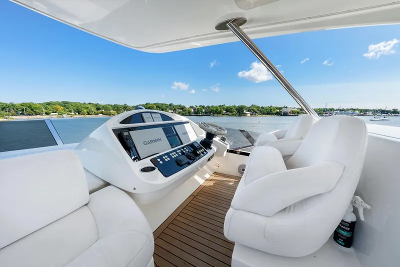 Slide: The Image of 2016 Sunseeker Manhattan 65 yacht helm with white seating and navigation controls, overlooking water. - 29