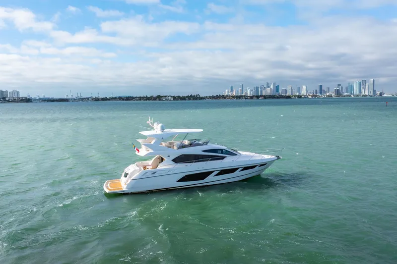 Slide: The Image of 2016 Sunseeker Manhattan 65 yacht cruising on open water with city skyline backdrop. - 3