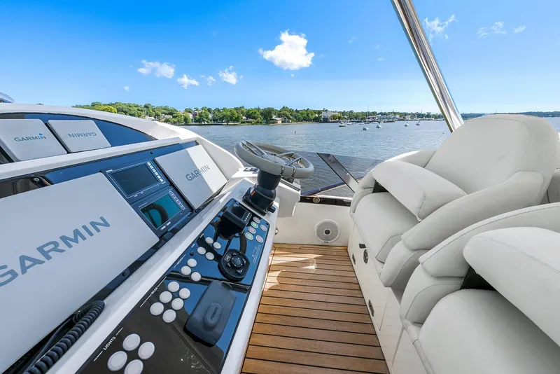 Slide: The Image of 2016 Sunseeker Manhattan 65 yacht helm with Garmin navigation, overlooking serene waters. - 31