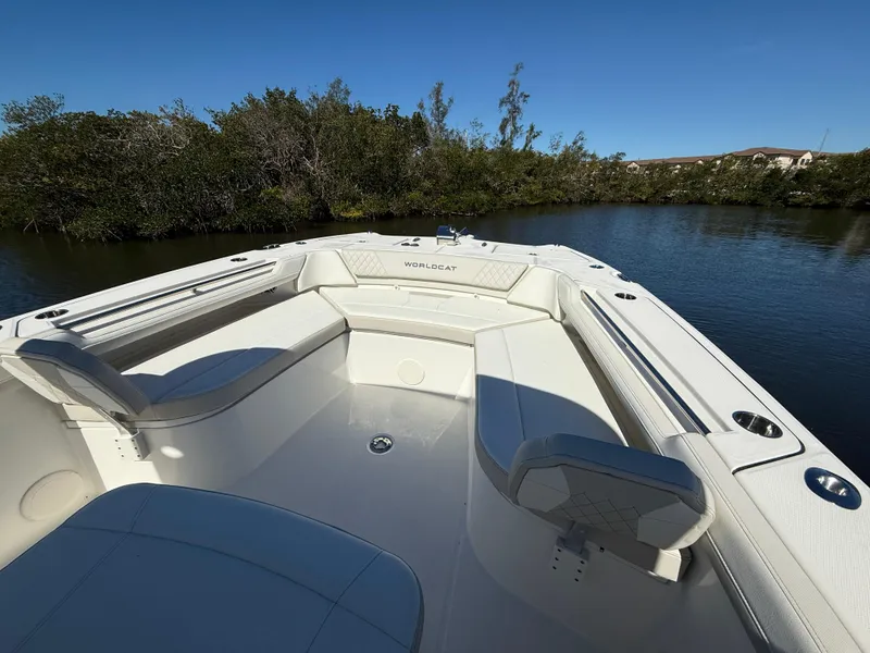 Slide: The Image of 2025 World Cat 325 CC boat interior with white seating, surrounded by calm water and trees. - 15