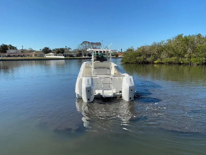 Slide: The Image of 2025 World Cat 325 CC boat on calm water, surrounded by greenery and clear blue sky. - 6