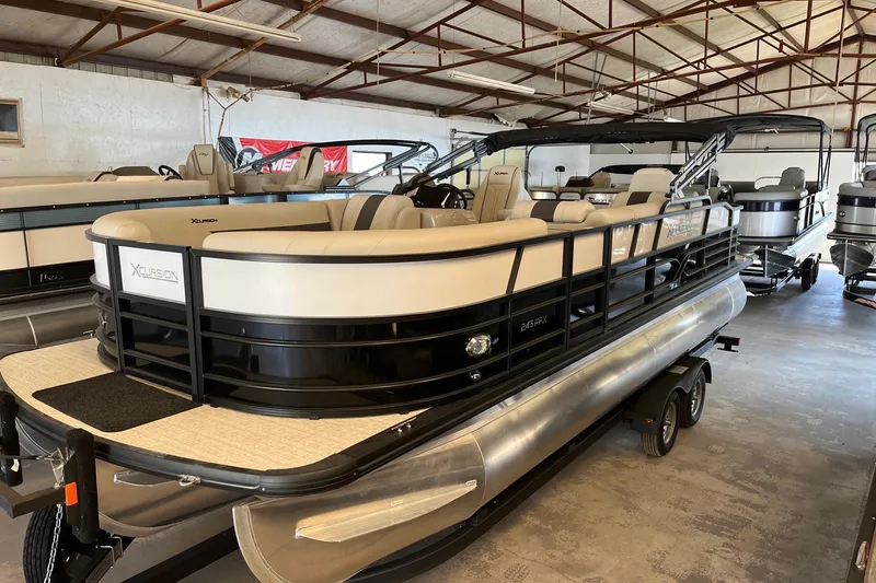 Slide: The Image of 2023 Xcursion 243 PFX pontoon boat in showroom, featuring sleek design and modern amenities. - 1