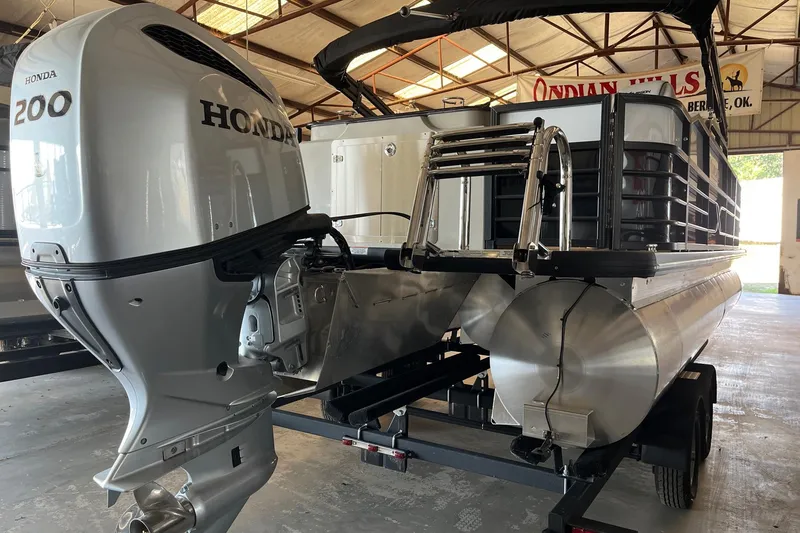 Slide: The Image of 2023 Xcursion 243 PFX pontoon boat with Honda 200 outboard motor in a warehouse. - 18