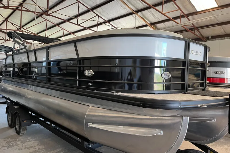 Slide: The Image of 2023 Xcursion 243 PFX pontoon boat in a warehouse setting. - 2