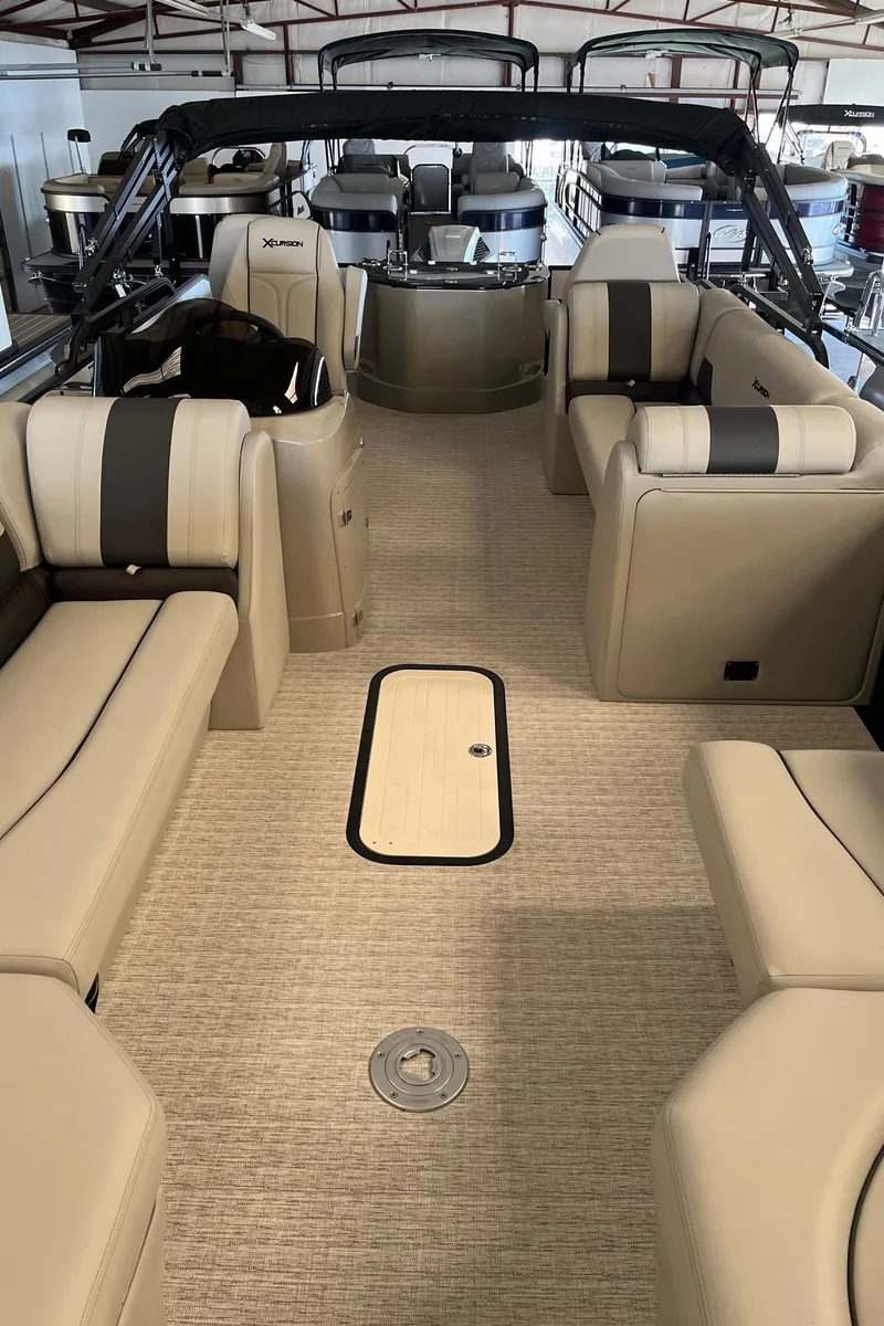 Slide: The Image of 2023 Xcursion 243 PFX pontoon boat interior with beige seating and spacious layout. - 6