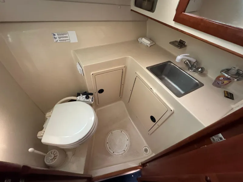Slide: The Image of 2005 Albin 28 Tournament Express boat bathroom with toilet, sink, and storage cabinets. - 25