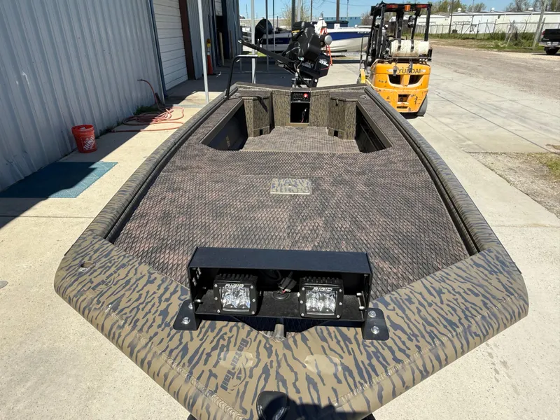 Slide: The Image of 2025 Gator Tail 1854 Extreme boat with camo design, docked near a warehouse. - 6