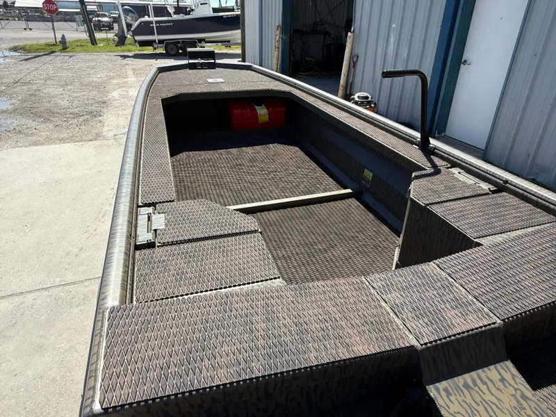 Slide: The Image of 2025 Gator Tail 1854 Extreme boat with textured flooring, docked near a metal building. - 7