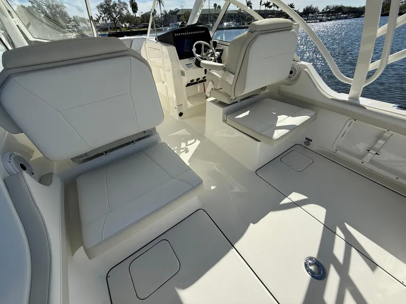 Slide: The Image of 2025 World Cat 296 DC boat interior with white seating and steering console, overlooking water. - 11