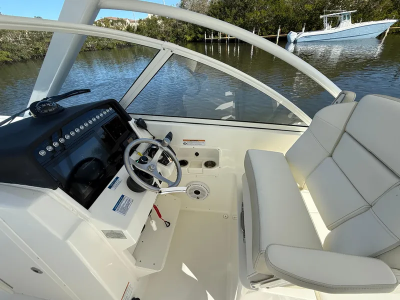 Slide: The Image of 2025 World Cat 296 DC boat interior with steering wheel and seating, on calm water. - 13
