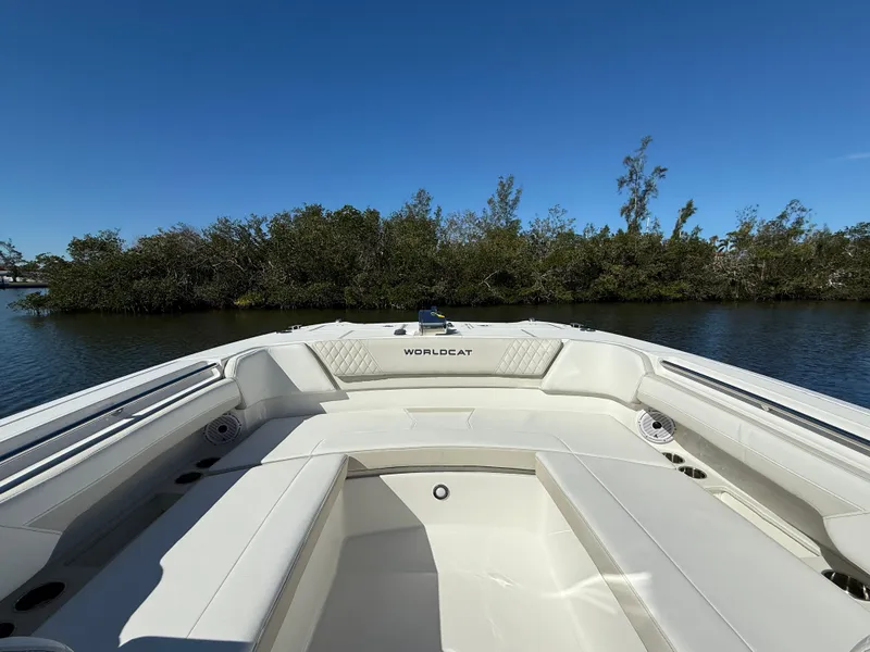 Slide: The Image of 2025 World Cat 296 DC boat on calm water, surrounded by lush greenery. - 18