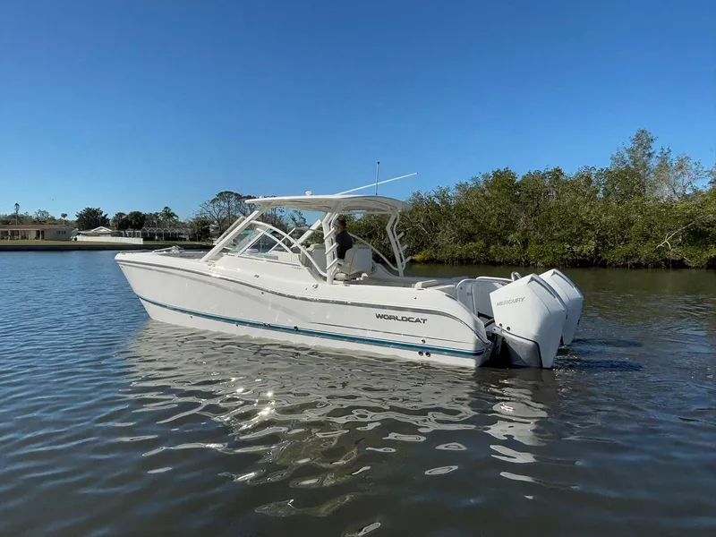 Slide: The Image of 2025 World Cat 296 DC boat on calm water, clear sky background. - 5
