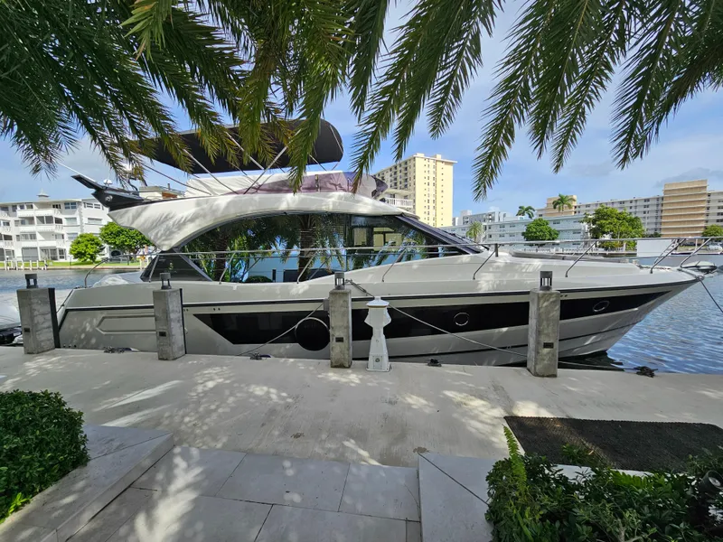 Slide: The Image of 2021 Beneteau Monte Carlo 52 yacht docked by waterfront, surrounded by palm trees. - 2