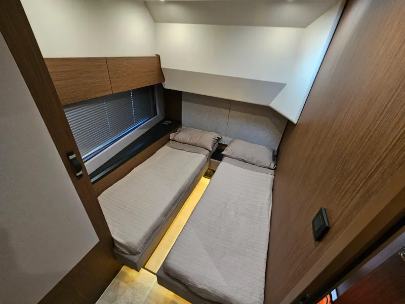 Slide: The Image of 2021 Beneteau Monte Carlo 52 cabin with twin beds, modern design, and ambient lighting. - 23