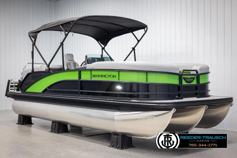 Slide: The Image of 2025 Bennington MFBSE pontoon boat with green accents and canopy in showroom. - 3