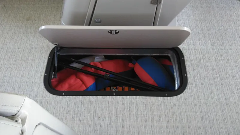 Slide: The Image of Open storage compartment on 2022 Xcursion 243RFX boat with life jackets inside. - 12