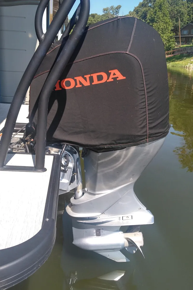 Slide: The Image of 2022 Xcursion 243RFX boat with Honda outboard motor cover on a calm waterway. - 15