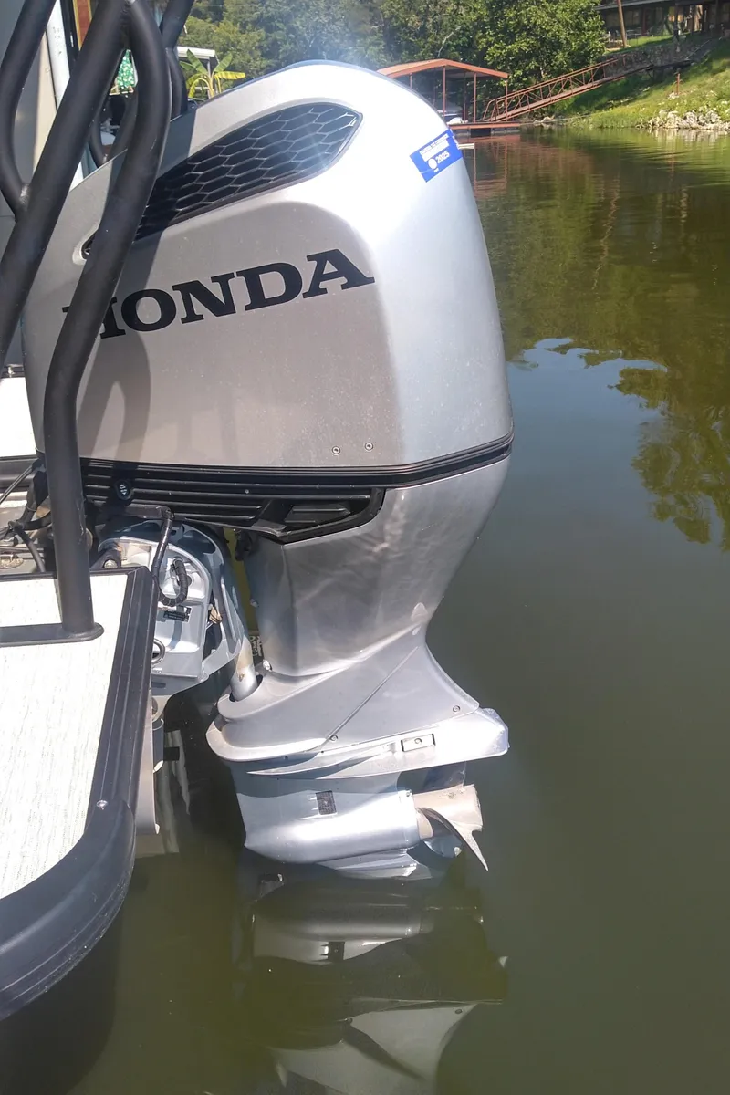 Slide: The Image of 2022 Xcursion 243RFX with Honda outboard motor on a calm lake. - 16