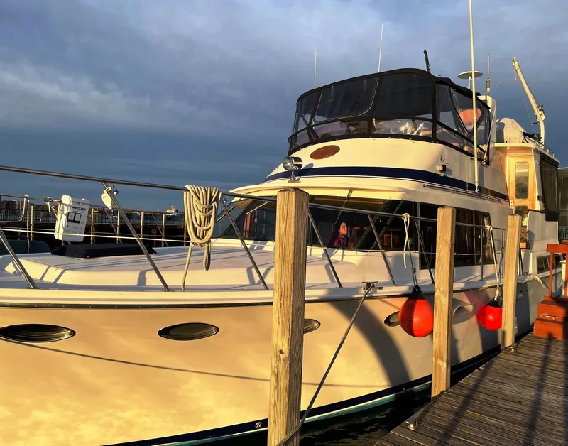 The Image of 1989 Marine Trader 47 CMY yacht docked at sunset with red fenders and wooden posts. - 0