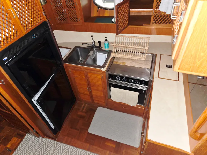 Slide: The Image of 1989 Marine Trader 47 CMY galley with sink, stove, and refrigerator in wooden cabinetry. - 16