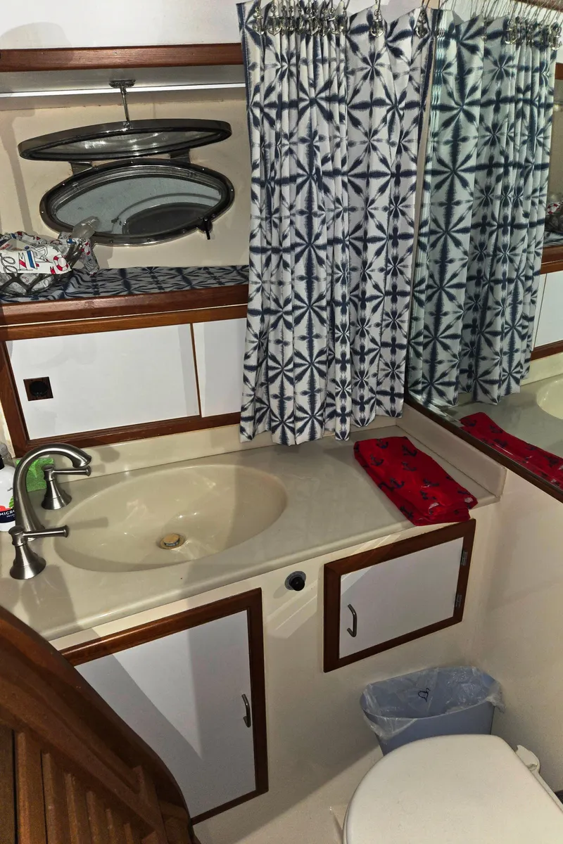 Slide: The Image of 1989 Marine Trader 47 CMY bathroom with sink, mirror, and patterned curtains. - 18