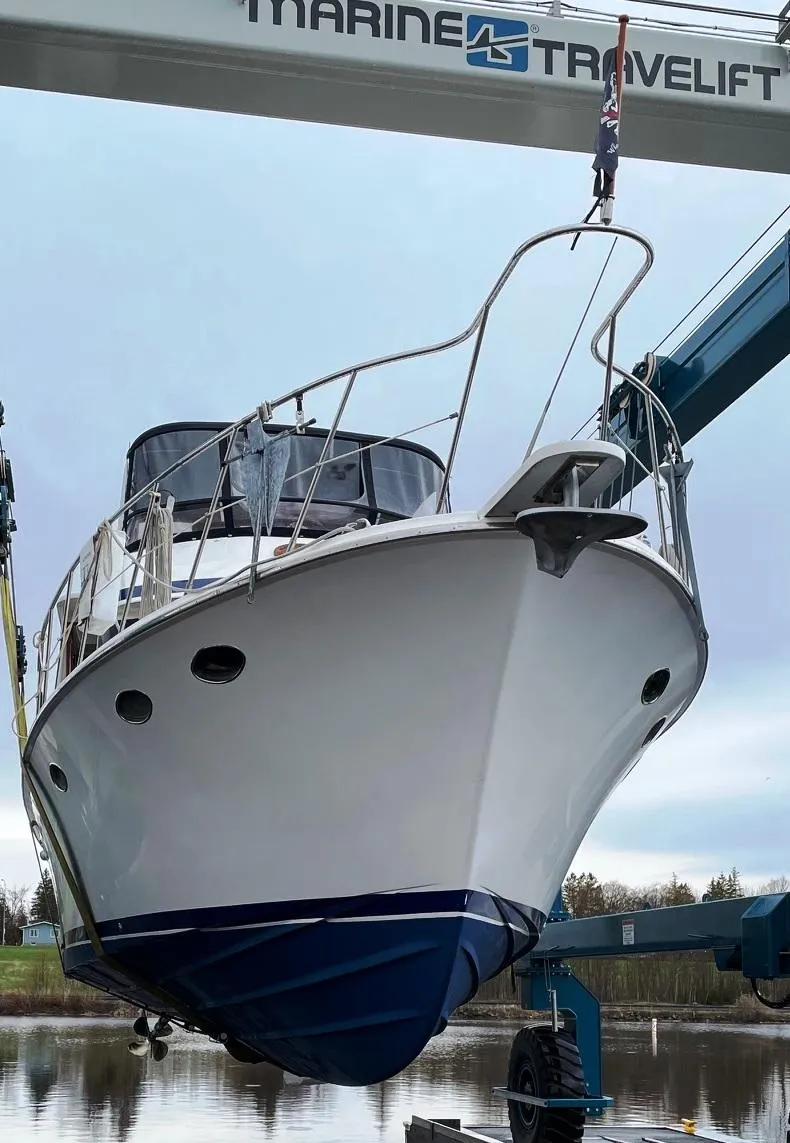 Slide: The Image of 1989 Marine Trader 47 CMY yacht being lifted by a travel lift at a marina. - 2