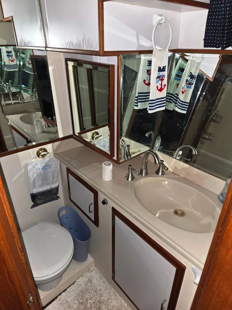 Slide: The Image of 1989 Marine Trader 47 CMY bathroom with sink, mirror, and nautical-themed decor. - 25