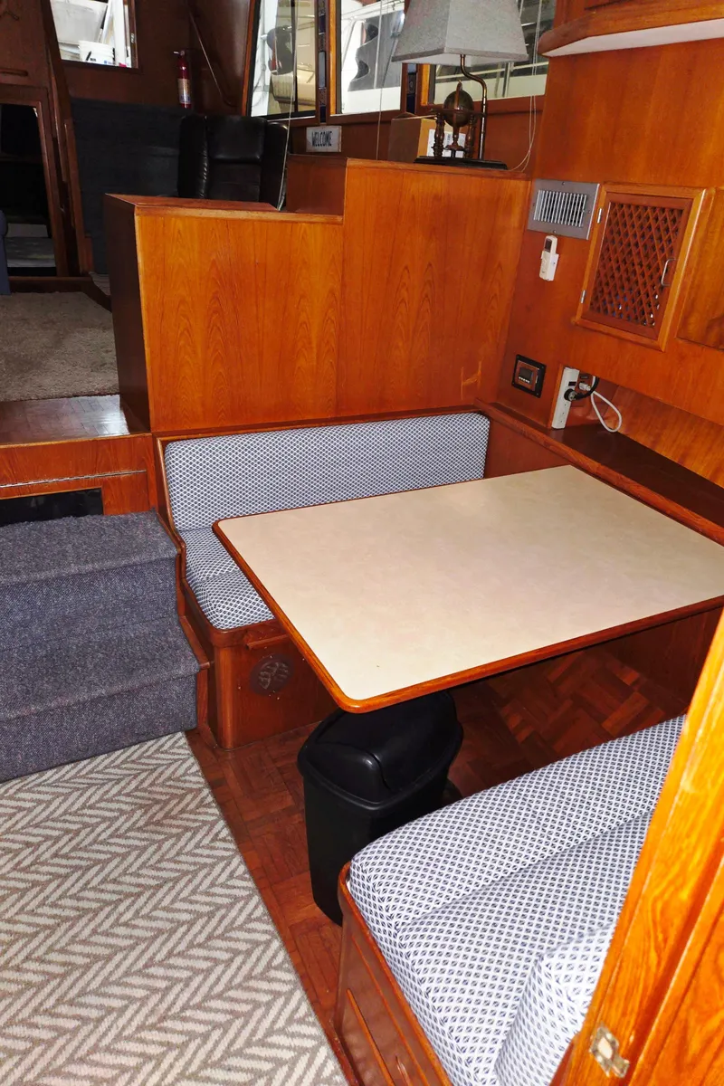 Slide: The Image of 1989 Marine Trader 47 CMY interior with wooden dining area and cushioned seating. - 28